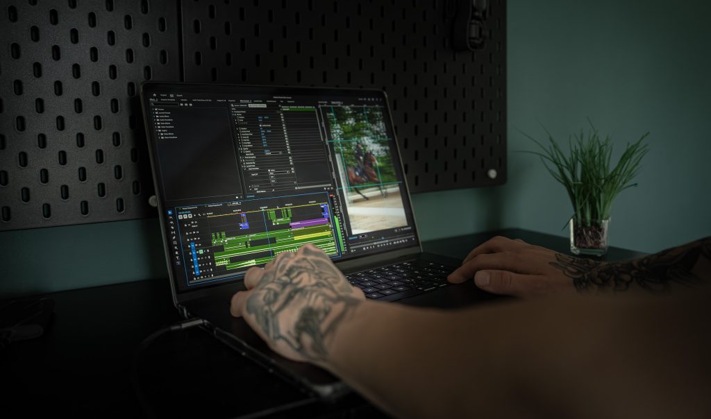 CineFlow. Hände eines Dicentia-Mitarbeiters am MacBook Pro bei Videobearbeitung und Postproduktion.